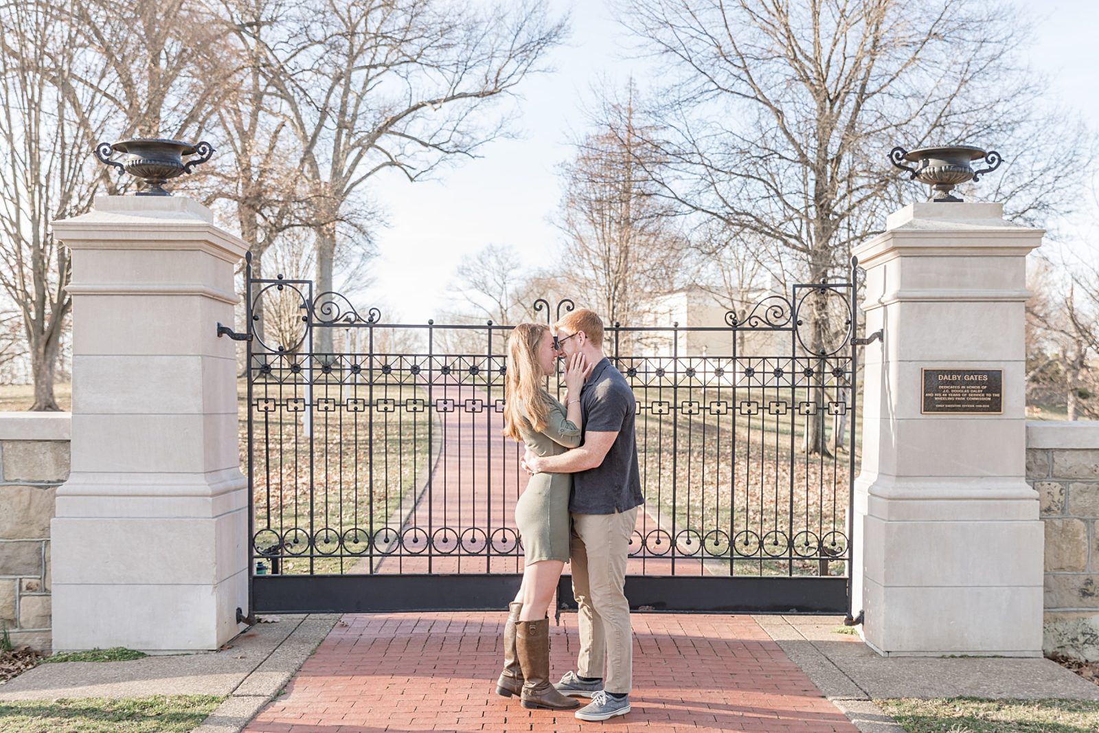 Engaged couple looking at each other in front of a gate