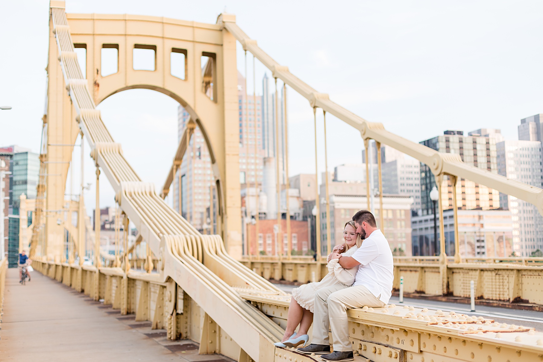 Engaged couple sitting snuggling on a yellow bridge