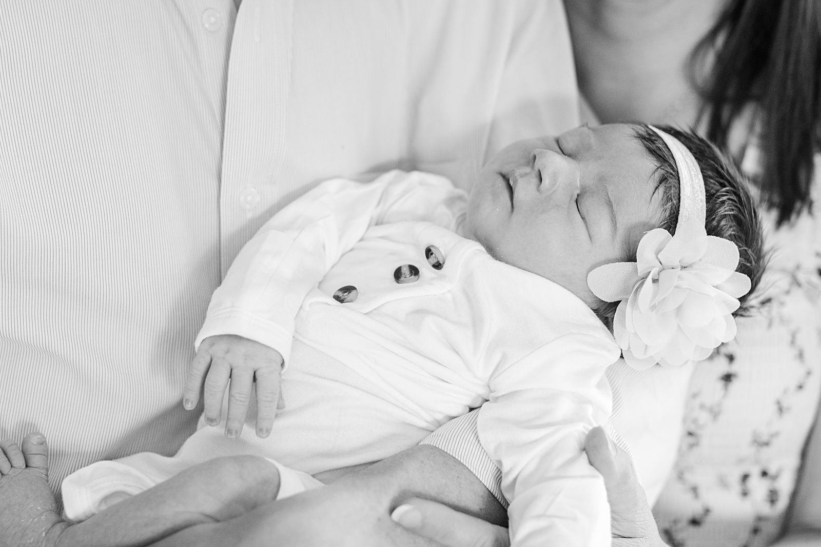newborn baby girl sleeping in her parents arms